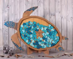 a wooden turtle with blue and turquoise pebbles in it's shell