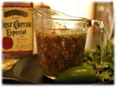 a glass pitcher filled with spices sitting on top of a counter next to some vegetables