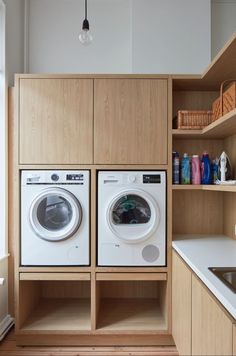 a washer and dryer in a kitchen with wooden cabinets on either side of the washer and dryer