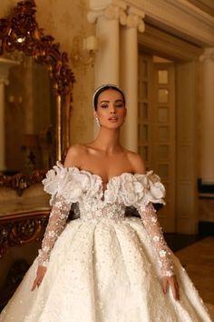 a woman in a white wedding dress standing next to a mirror and looking at the camera