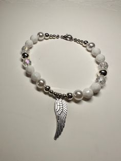 "This is a beautiful OOAK handmade beaded bracelet with an Angel wing charm. The pearl beads really make the silver and clear beads shine! Very pretty white and silver color with  clear beads for accent on a stretchy elastic but has a clasp as well. Also features an Angel wing charm. Will fit a 7\" wrist. Picture taken in different lighting to show how it looks under different settings. We offer free shipping on all of our items! If you are interested in a certain color combination, please send Silver Beaded Pearl Stretch Bracelet, Silver Pearl Stretch Bracelet Gift, Silver Pearl Stretch Bracelet As Gift, Silver Pearl Stretch Bracelet For Gift, Homemade Necklaces, Angel Bracelet, Spider Necklace, Beaded Angels, Punk Accessories