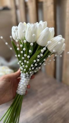 a bouquet of white tulips and baby's breath is held by a hand