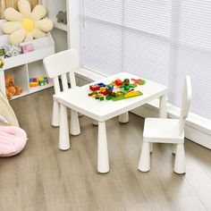 a child's table and chairs in a playroom with toys on the floor