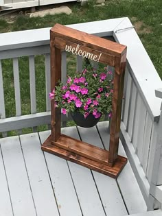 a small mirror with some flowers in it on a wooden porch next to a fence