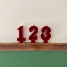 three candles with the number 123 on them are sitting in front of a green wall