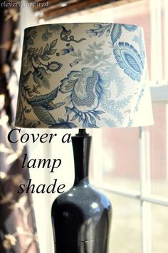 a lamp shade sitting on top of a window sill next to a black vase