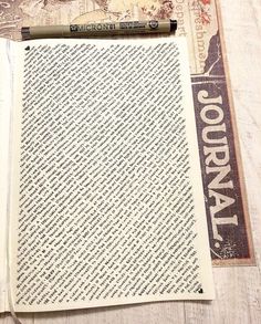 an open book sitting on top of a wooden table next to a marker and pen