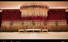 the wedding stage is decorated with red flowers and gold chairs