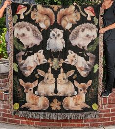 two women standing next to a blanket with animals on it