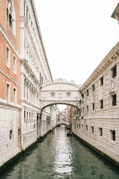 a narrow canal in the middle of a city with buildings on both sides and a bridge over it