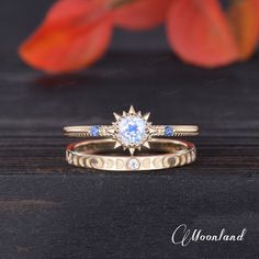 two gold rings with blue and white stones on them sitting next to an orange flower