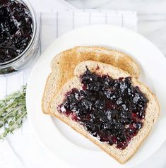 two pieces of toast with jam on them sitting on a plate next to a jar of jelly