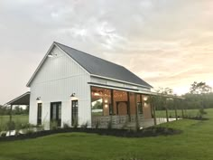 a small white house sitting on top of a lush green field under a cloudy sky