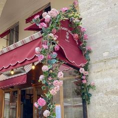 pink flowers are growing on the outside of a building with awnings and windows