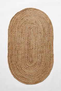 the oval rug is made out of jute and has been placed on a white surface