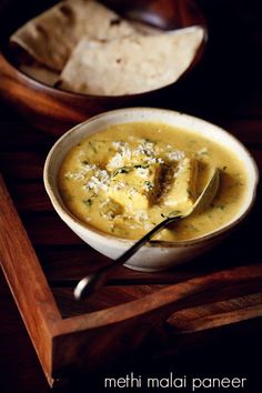 there is a bowl of soup with tortilla chips on the side and a spoon in it