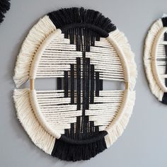 two black and white wall hangings with tassels on the sides, one in the shape of a circle