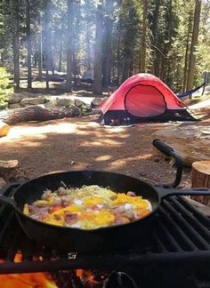 a pan filled with food sitting on top of a grill next to a campfire