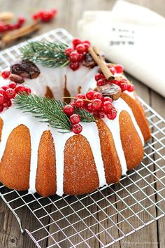 a bundt cake with white icing and cranberries on a cooling rack