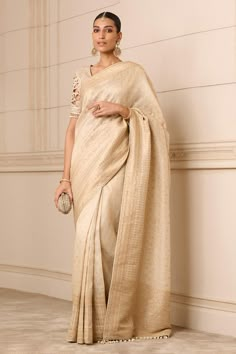 Beige hand embroidered saree featuring floral motifs and pearl tassels on the border. Paired with a textured blouse in tulle and silk with cutwork sleeves and pearl tassels., Fit: Relaxed Luxury Slub Silk Saree With Border, Luxury Tissue Silk Saree With Cutdana, Luxury Tissue Silk Saree With Self Design, Luxury Beige Saree With Zari Weaving, Luxury Beige Blouse Piece With Pallu, Luxury Beige Tissue Silk Traditional Wear, Luxury Elegant Tissue Silk Saree, Luxury Pre-draped Tissue Silk Saree, Luxury Transitional Tissue Silk Blouse Piece