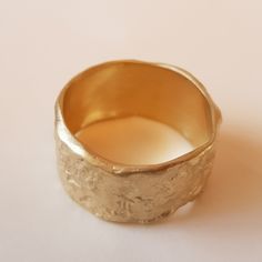 Organic form meets expert craftsmanship with this stunning solid 18K gold women's wedding band. A subtle yet sensational statement, this piece has an apparent weight and impressive width with naturally undulating sides and a rough-textured surface. Each ring is handcrafted and one of kind just like the singular union they represent. ◈ DETAILS Weight: 6g Width: 12-13mm / 0.47''- 0.51'' Thickness: 1.1-1.5mm / 0.39''- 0.06'' ◈ MATERIAL 18K Solid Gold ◈ ALSO AVAILABLE IN 14K Yellow, Rose, or White G Organic Gold Ring, Statement Gold Ring, Thick Band Ring, Hammered Wedding Band, Wide Gold Ring, Textured Gold Ring, Hammered Gold Ring, Hammered Wedding Bands, Gold Ring For Women