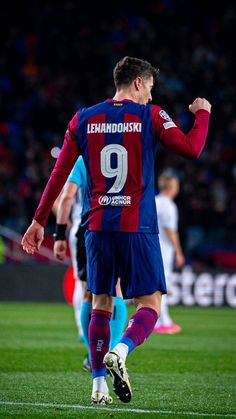 a soccer player is walking on the field with his arms in the air as he celebrates