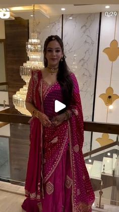 a woman in a pink outfit standing next to a chandelier