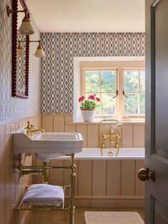 a bathroom with a tub, sink and window in it's wallpapered walls