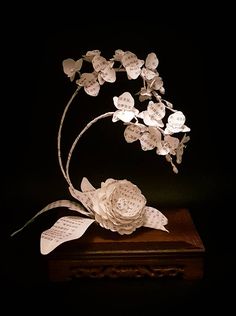 a sculpture made out of sheet music and paper flowers on top of a wooden box