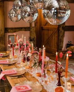 a long table is set with pink napkins and place settings in front of mirrored disco balls