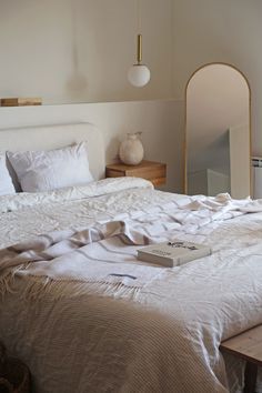 a white bed sitting under a window next to a mirror