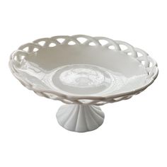 a white bowl sitting on top of a table next to a plate with a circular design