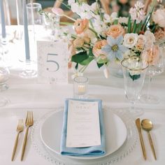 the table is set with silverware and flowers