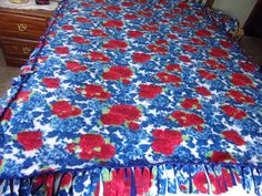 a bed with red and blue flowered bedspread on top of it in a bedroom