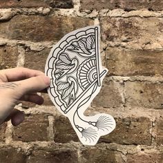 a hand holding up a sticker with an intricate design on it