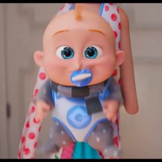 a close up of a baby doll with blue eyes and a pacifier in its mouth