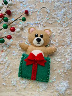 a brown teddy bear sitting on top of a green box with a red bow hanging from it's side