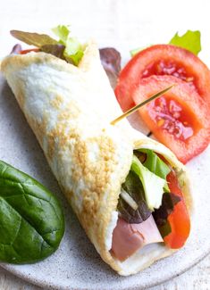 a close up of a sandwich on a plate with tomatoes and lettuce next to it