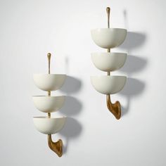 three white bowls with gold handles are hanging on the wall, and there is no image here to provide a caption for