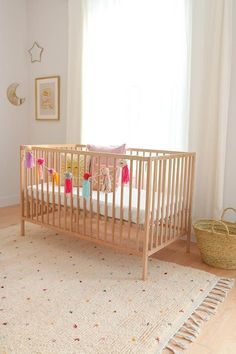 a baby's crib in the corner of a room with white walls and wooden floors