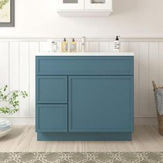 a bathroom with a blue cabinet and white counter top next to a rug on the floor