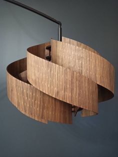 a circular wooden light fixture hanging from the ceiling in a room with grey walls and flooring