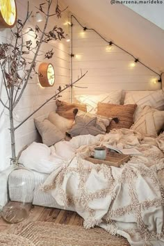 a bed with pillows, blankets and lights on the headboard in a loft bedroom