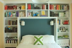 a bed with bookshelves behind it and a green pillow on the headboard