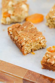 several pieces of granola bar sitting on top of a piece of parchment paper next to carrots