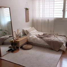 a bedroom with a bed, dresser and mirror on the floor in front of a window