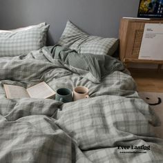 an unmade bed with a book and two cups on it