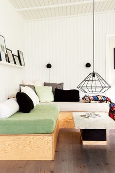 a living room with white walls and wood flooring is decorated in black, white, and green