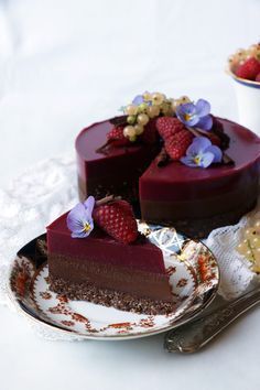 two slices of chocolate cake with strawberries and flowers on the plate next to each other