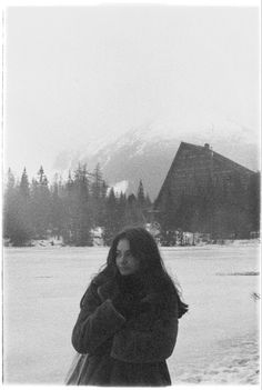 a black and white photo of a woman standing in the snow with her arms around her neck